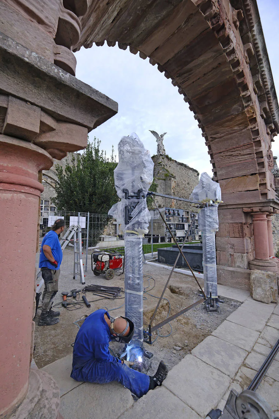 Uno de los trabajadores sujeta un pilar con el Ángel de Llimona de fondo. 